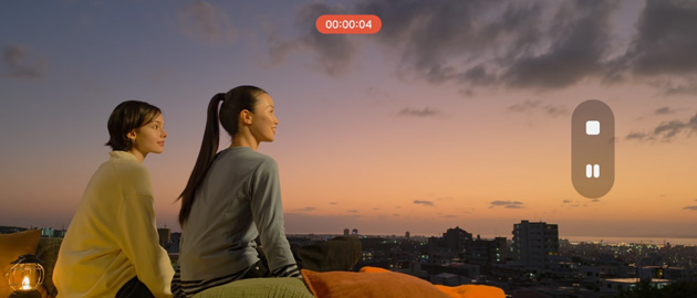 An 8K low-light video frame of a person sitting on a rooftop at sunset. The S26 Ultra captures sharp facial details and fine knit textures in their sweater against a vibrant orange and hazy city background.