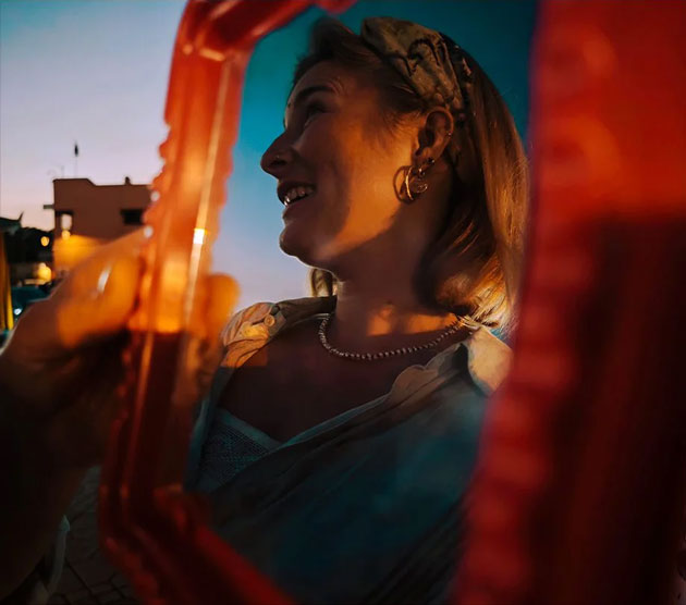 A creative portrait captured on the Xiaomi 15 Ultra framed through a blurred orange object in the foreground A creative portrait captured on the Xiaomi 15 Ultra, framed through a blurred orange object in the foreground.