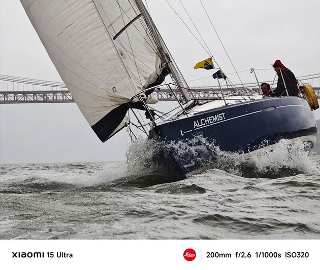 A dynamic action shot of a sailboat named Alchemist leaning into a swell captured with the Xiaomi 15 Ultras 200mm telephoto lens A dynamic action shot of a sailboat named 'Alchemist' leaning into a swell, captured with the Xiaomi 15 Ultra's 200mm telephoto lens.