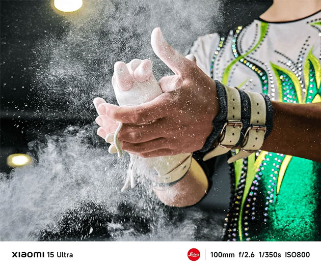 A high speed action detail shot captured with the Xiaomi 15 Ultras 100mm telephoto lens A high-speed action detail shot captured with the Xiaomi 15 Ultra's 100mm telephoto lens. The photo shows a gymnast's hands mid-motion, covered in white chalk powder that is exploding into a fine mist against a dark background.