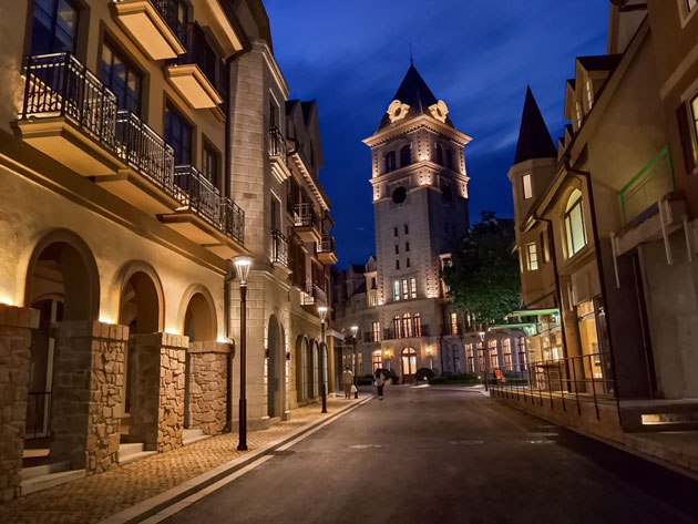 A night-time camera sample from the Realme C71 showing a European-style street with lit stone buildings, a clock tower, and a deep blue twilight sky.