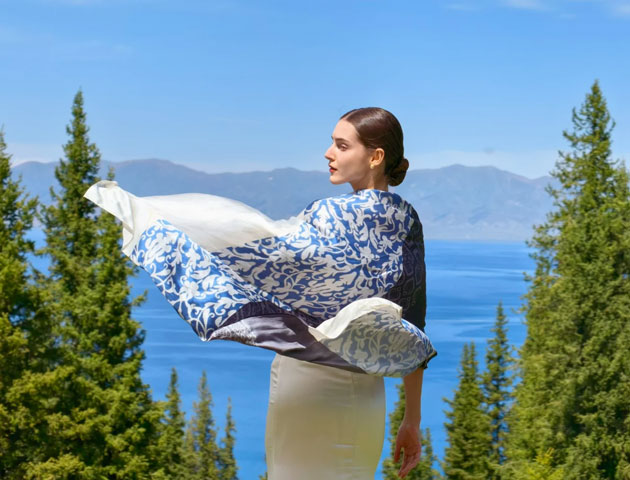 A photo taken with the Huawei Pura 80 Ultra. The image shows a woman from behind looking toward a blue lake and mountains A photo taken with the Huawei Pura 80 Ultra. The image shows a woman from behind, looking toward a blue lake and mountains.