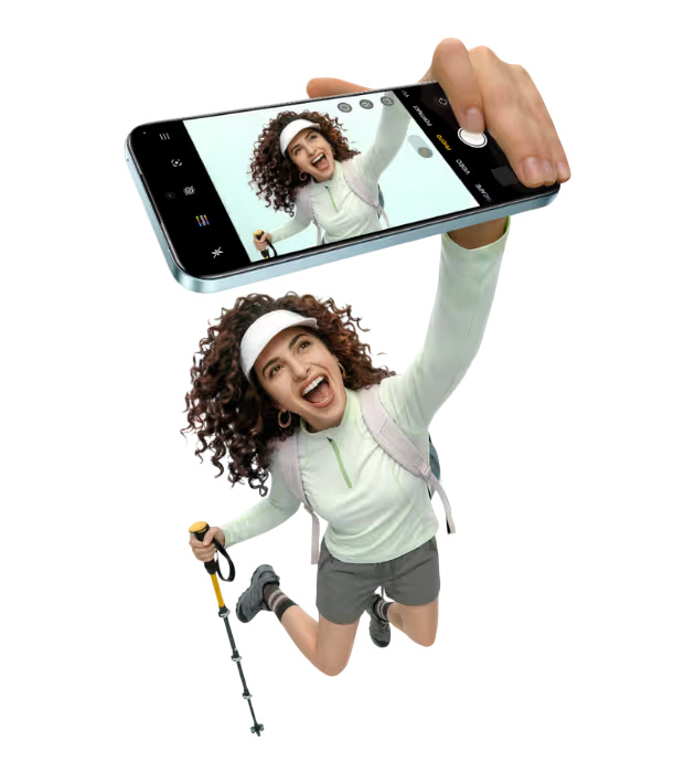A female hiker taking a selfie with her Realme 16T Aurora Green while jumping in the air.