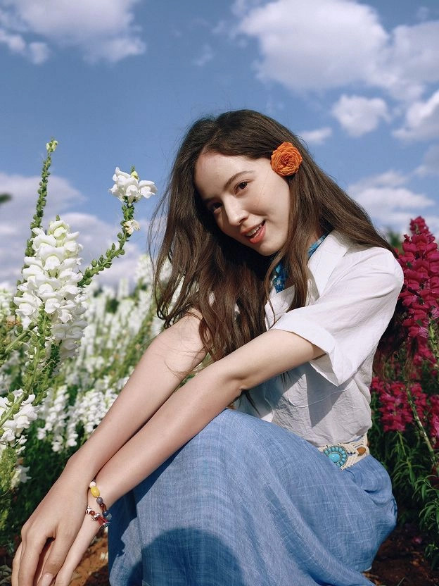A portrait photo taken outdoors beside colorful flowers with the OPPO Find X9 Ultra camera