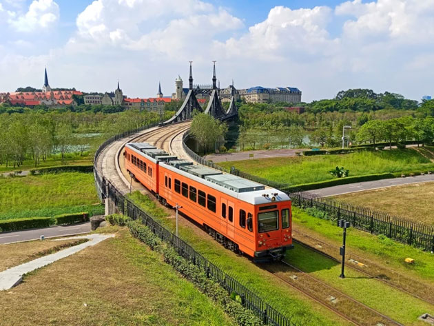 Daytime landscape photo taken with the Realme C75 showing a vibrant orange tram crossing a curved bridge Daytime landscape photo taken with the Realme C75 showing a vibrant orange tram crossing a curved bridge.