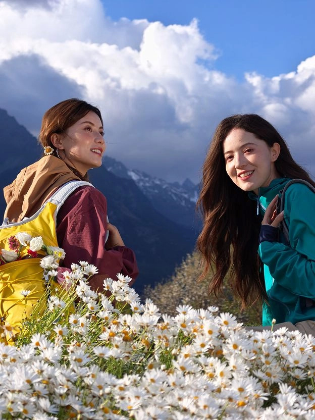 Two people beside white flowers on a mountainside under cloudy skies; photo taken with OPPO Find X9 Ultra camera