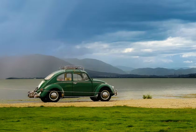 A photo taken with the Honor X9d camera showing a green Volkswagen Beetle by a lake and mountains under a cloudy sky A photo taken with the Honor X9d camera showing a green Volkswagen Beetle by a lake and mountains under a cloudy sky.