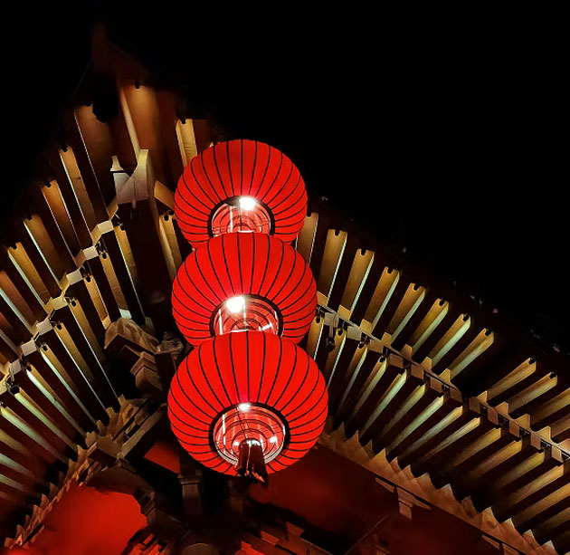 A photo taken with the Honor X9ds Night Mode featuring three bright red paper lanterns under a wooden roof in the dark A photo taken with the Honor X9d's Night Mode featuring three bright red paper lanterns under a wooden roof in the dark.